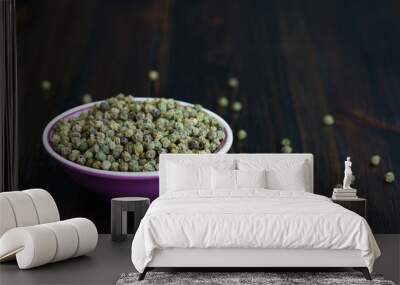 Dried green peppercorns in a violet bowl. Dark wooden table, high resolution, negative space Wall mural