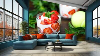 Whipped cream and strawberries served in a glass. Dark wooden table, tennis ball in bokeh, high resolution Wall mural