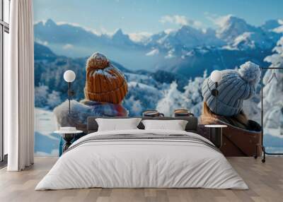 People in warm clothes hold a mug of hot drink and look at the snowy mountain landscape.  Wall mural