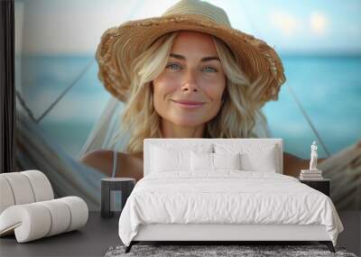 Woman relaxing in a hammock on the beach wearing a straw hat. Wall mural