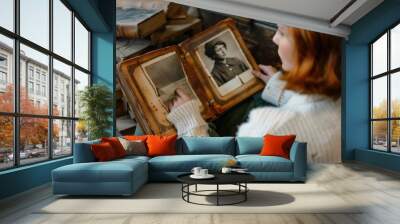 Woman viewing old black and white photos in a vintage photo album. Wall mural