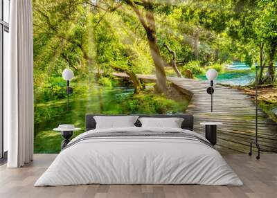 Wooden footpath over river in forest of Krka National Park, Croatia. Beautiful scene with trees, water and sunrays. Wall mural