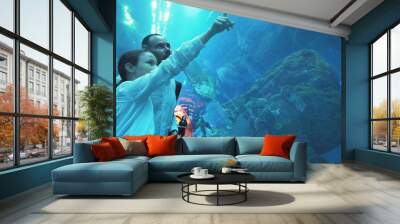 Teenage girl with Dad amusingly watching the fish in Aquarium Wall mural