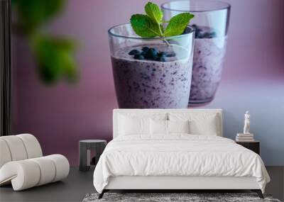 two glasses of homemade smoothie with fresh blueberries with mint leaves on pastel pink background. Wall mural