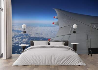 Airplane above the clouds on the sky background Wall mural