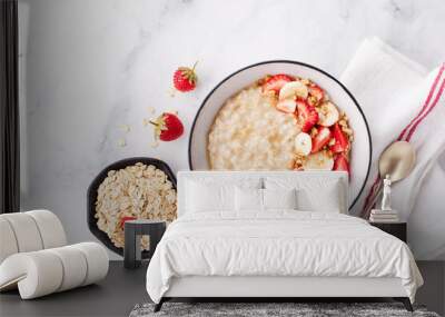 Bowl of oatmeal porridge with strawberry and banana on white table top view. Healthy and diet breakfast. Wall mural