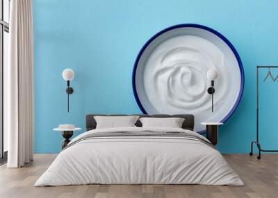 Greek yogurt in bowl on blue table top view. Wall mural