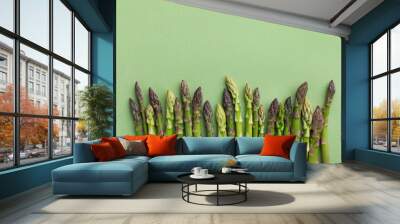 Heap of fresh asparagus on green background top view. Healthy food in flat lay style. Wall mural