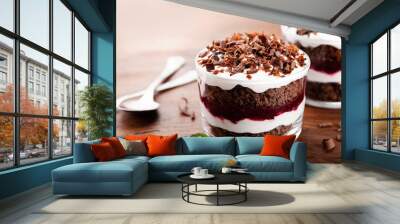 Layered trifle dessert with chocolate sponge cake, whipped cream and fruit jelly in serving glasses. Wall mural