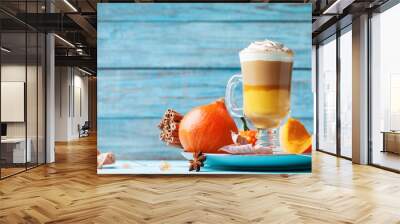 Pumpkin spiced latte or coffee in glass on turquoise wooden table. Autumn, fall or winter hot drink. Wall mural