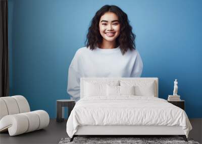 Young woman wearing white sweatshirt mockup isolated on blue background. Generative AI. Wall mural