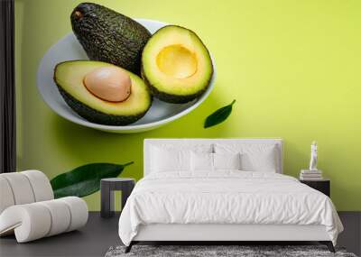 Avocado inside ceramic pot on green background. Wall mural