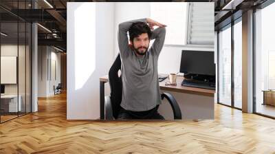 Handsome hispanic doing stretching during work at home. Wall mural