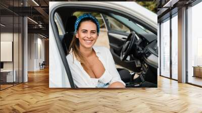 Young female co-driver, sitting in a white car with an open door Wall mural