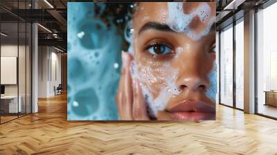 Beautiful black girl wash her face with cleansing face foam. young woman looking at camera. Concept of face skin care. horizontal isolated on blue water background. Studio shoot. Wall mural