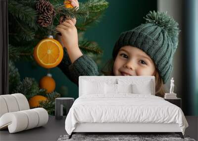 Joyful Child Decorating Christmas Tree with Oranges in Cozy Winter Attire, Capturing Holiday Spirit and Sustainable Decor Trends Wall mural