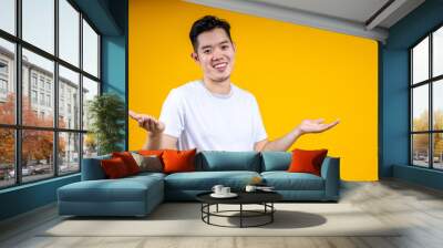 Young handsome Asian man with beard over isolated yellow background points finger at you while smiling Wall mural