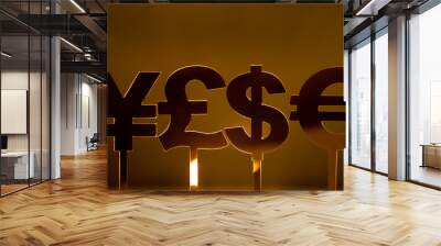 Close-up of four different currency symbols: the U.S. dollar, the British pound, the Euro,and the Japanese yen, on sticks in front of a gold background Wall mural