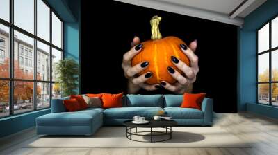 Happy Halloween theme. Witches knotty hands with black sharp long nails hold a small pumpkin, low key, selected focus. Wall mural