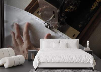 Sewing process. Foot of old vintage sewing machine and hand. Selective focus Wall mural