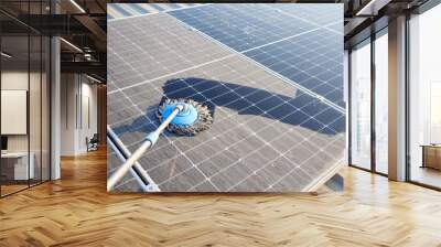 Man clean up the solar panels that are dirty with dust and birds' droppings to improve the efficiency of solar energy storage. Wall mural