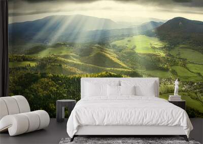 Landscape and nature in the spring. Landscape with dramatic sky and green meadows. The sun rays through the clouds. Wall mural