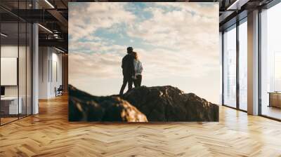 Young couple holding each other on beach at sunset Wall mural