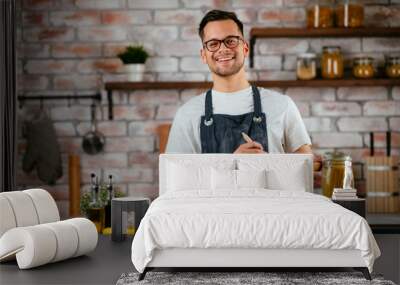 Attractive man cooking in modern kitchen. Handsome chef preparing food. Wall mural