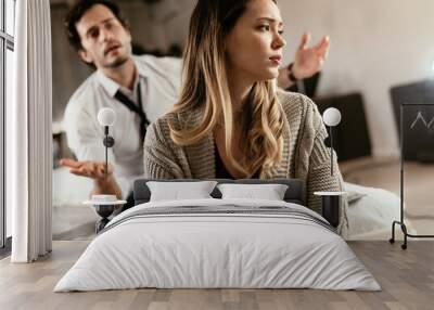 Boyfriend and girlfriend are arguing at home. Angry man is yelling at his sad girlfriend. Wall mural