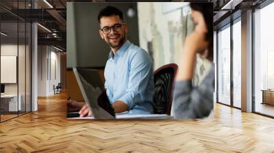 Colleagues in office. Businesswoman and businessman discussing work in office. Two friends working together Wall mural