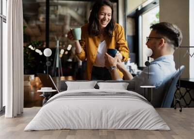 Colleagues laughing in office. Businesswoman and businessman drinking coffee.. Wall mural