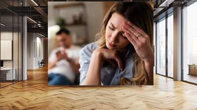 Couple at home after having a fight. Sad depressed woman sitting on sofa.. Wall mural