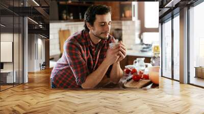 Handsome man preparing breakfast at home. Young man drinking coffee and enjoying in the morning.. Wall mural