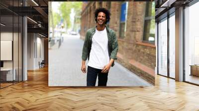 Handsome young man with headphones. Man listening the music while walking through the city Wall mural