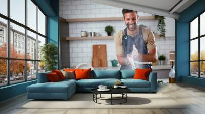 Happy man baking in the kitchen. Man making delicious food at home.. Wall mural