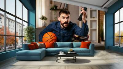 Happy man enjoying at home. Man watching sports game on tv Wall mural