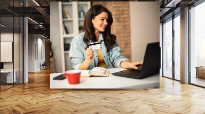 Pregnant woman shopping online at home. Happy woman with laptop and credit card Wall mural