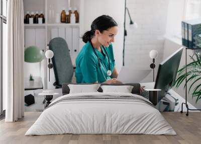 Young beautiful doctor in medical office. Female doctor working on analysis.  Wall mural