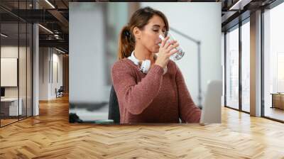 Young businesswoman drinking water in office Wall mural