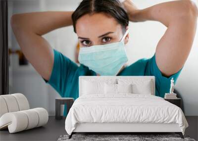 Young female doctor in medical office. Beautiful female doctor putting mask on. Close up. Wall mural