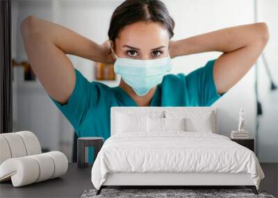 Young female doctor in medical office. Beautiful female doctor putting mask on. Close up. Wall mural