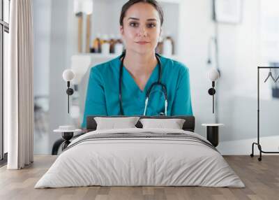 Young female doctor in medical office. Portrait of beautiful female doctor sitting in the clinic office. Wall mural