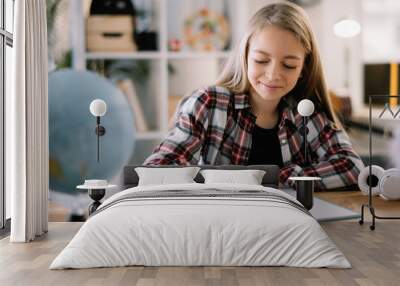 Young girl doing homework. Beautiful little girl at home learning  Wall mural