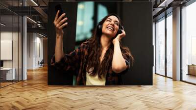 Young smiling woman with headphones outdoors. Beautiful happy girl listening the music Wall mural