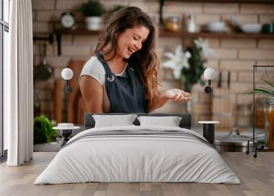 Young woman in kitchen. Beautiful woman having fun while making  dough. Wall mural