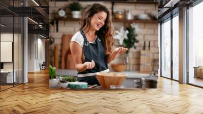 Young woman in kitchen. Beautiful woman having fun while making  dough. Wall mural