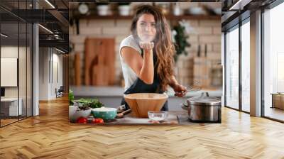 Young woman in kitchen. Beautiful woman playing with flour. Wall mural