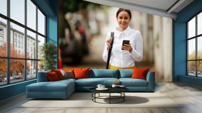 Young woman walking on the street using phone Wall mural