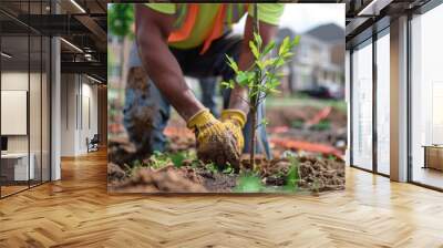 A closeup of a construction worker carefully planting a tree in a newly developed neighborhood emphasizing the importance of incorporating green spaces into urban landscapes for the . Wall mural