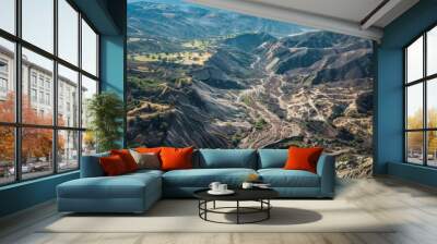 A dramatic aerial view of the mountainous terrain reveals the devastating aftermath of a series of mudslides with deep scars and altered landscapes. Wall mural